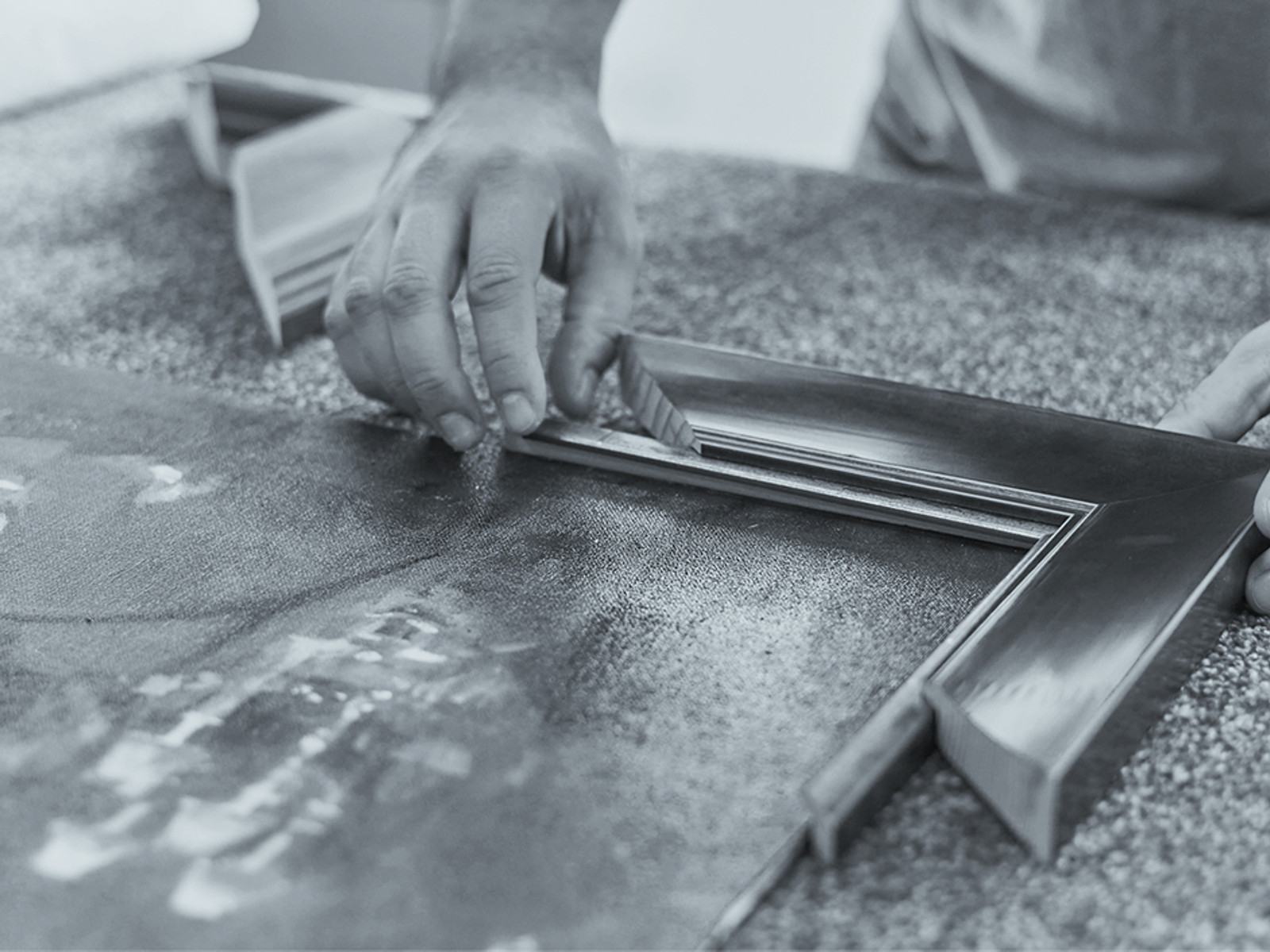 A Speedframe craftsperson joining a metal frame corner over a canvas on the workshop bench